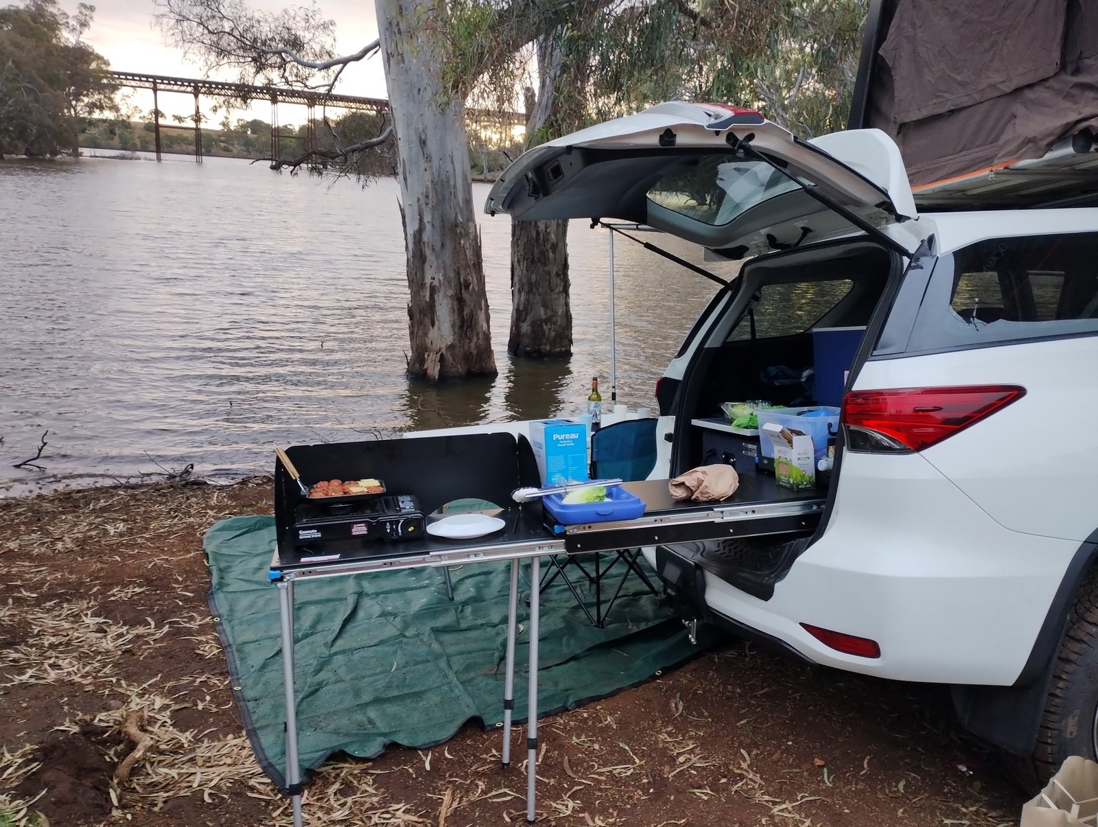 Rooftop tent and kitchen set up beside a river